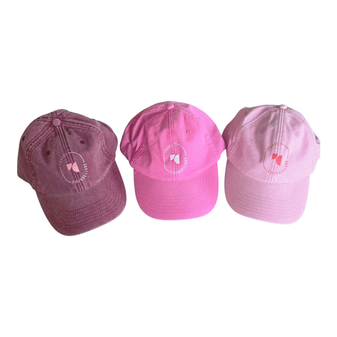 Well Travelled Wallets baseball caps in berry, bright pink, and light pink cotton with embroidered logo detail.